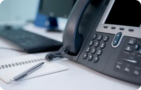 SIP trunking office desk with a VoIP phone, notepad, and pen, representing Session Initiation Protocol for internet telephony.