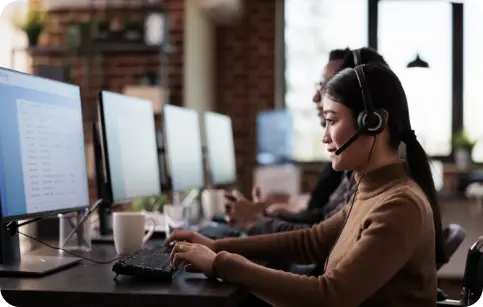 VOIP call center agent wearing a headset working on a computer, representing Voice over Internet Protocol communication.